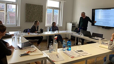 Vortragender steht bei Bildschirm