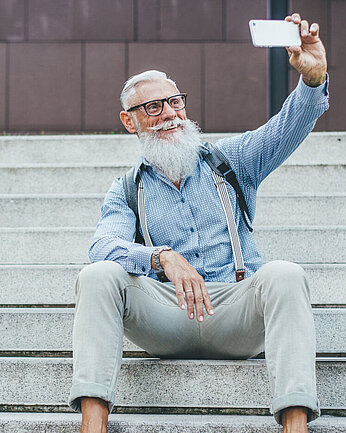Älterer Herr mit Brille macht ein Selfie