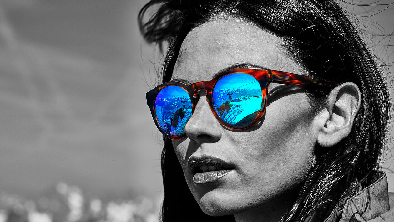Portrait einer Dame in schwarz/weiß, nur die Sonnenbrillengläser sind balu