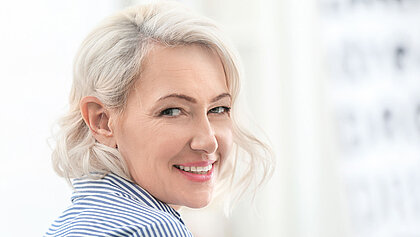 Eine ältere Dame lächelt in die Kamera