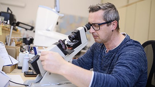 Ein Mann schaut durch Mikroskop
