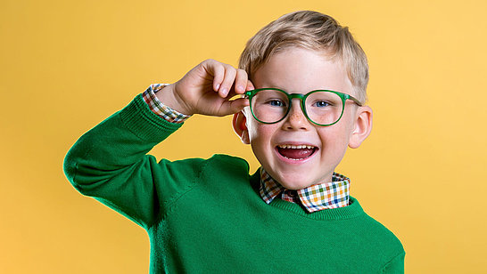 Ein Junge mit Brille vor gelbem Hintergrund