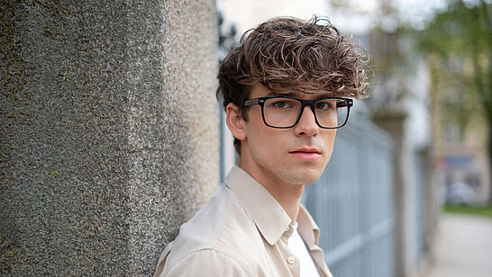 Junger Mann mit eckiger Brille im Freien