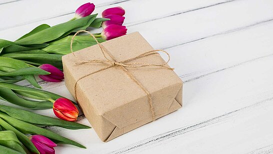 Geschenkbox neben Tulpen