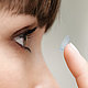 Nahaufnahme einer Frau, die sich Kontaktlinsen einsetzt
