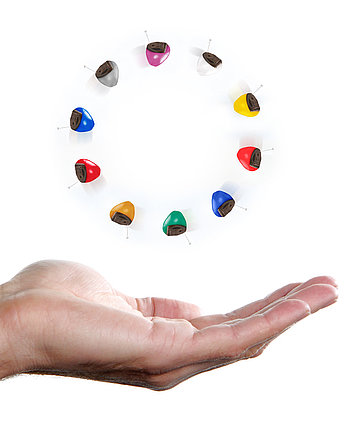 Hörgeräte in verschiedenen Farben auf einer Hand