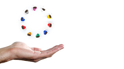 Hörgeräte in verschiedenen Farben über einer Hand