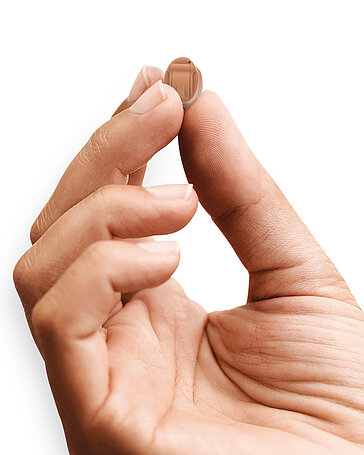 Eine Hand hält ein Hörgerät