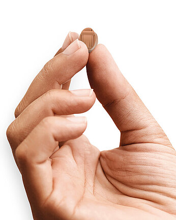 Eine Hand hält ein Hörgerät