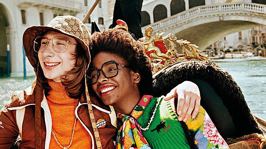 Ein Paar umarmt sich auf einer Gondel in Venedig, beide tragen ausgefallene Gucci Brillen