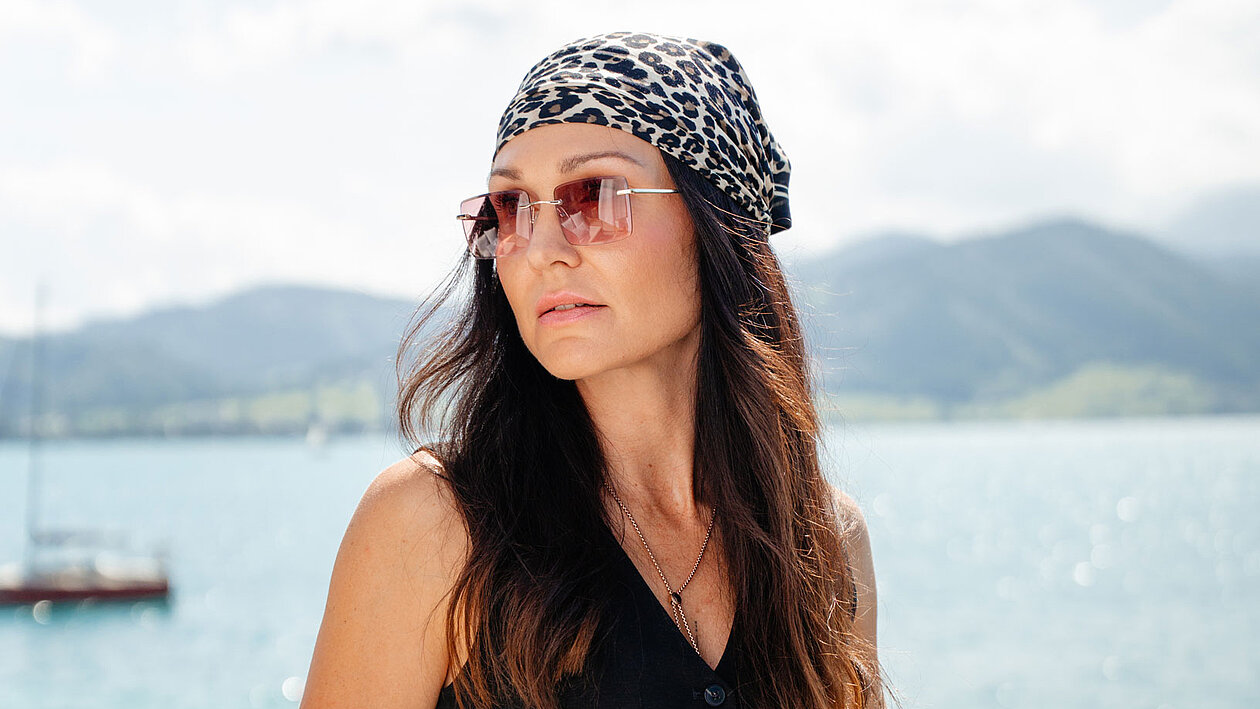 Junge Dame mit rosa Sonnenbrille vor einem See
