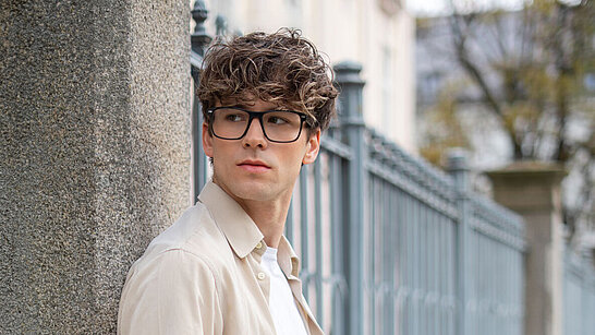 Junger Herr mit eckiger Brille im Freien