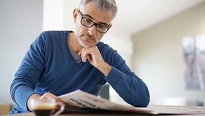 Ein älterer Herr mit Brille liest Zeitung